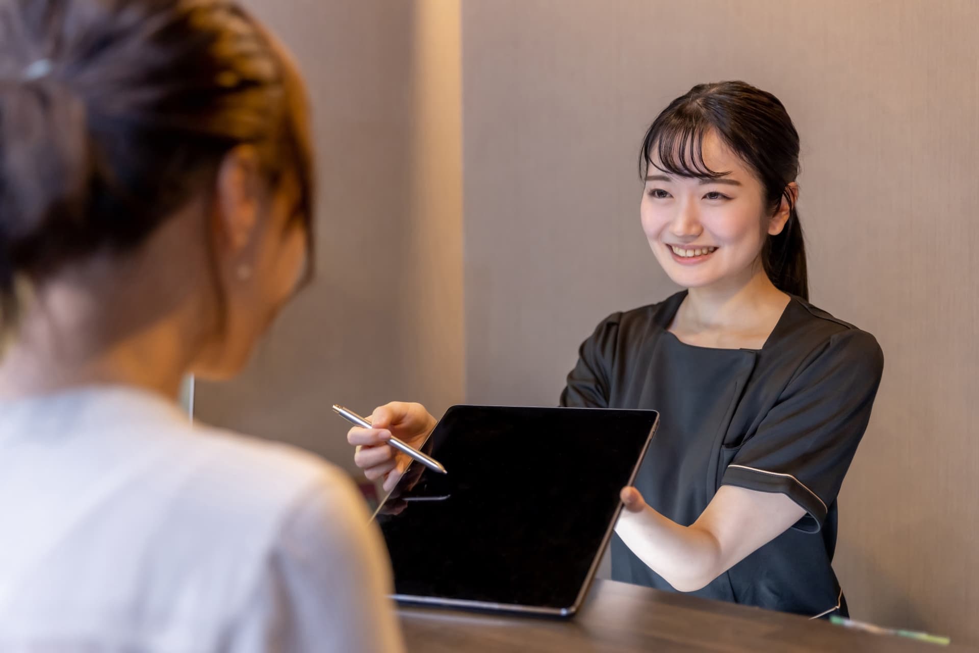 スタッフの女性がタブレットで料金を説明する